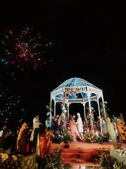 The wedding mandap lit up by a spectacular firework display against the night sky. We coordinate these grand moments to create a truly cinematic experience for you and your guests.