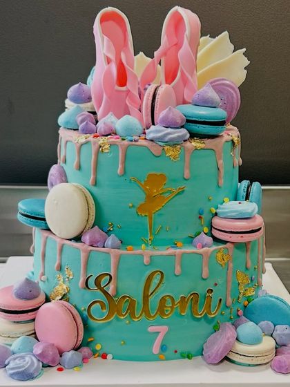 A vibrant two-tier ballerina cake for Saloni's 7th birthday, adorned with macarons, meringues, and a beautiful drip effect.