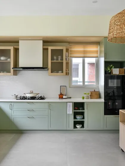 This kitchen from our 'House of Kismish' project exudes a European cottage vibe with its sage green cabinetry and delicate piccolo tiles. The design includes open shelving and a dedicated breakfast nook.