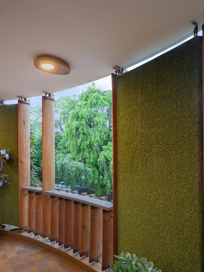 The balcony of the Outré House offers a private outdoor space where residents can connect with nature. The green wall panels and wooden railings continue the building's core design theme.