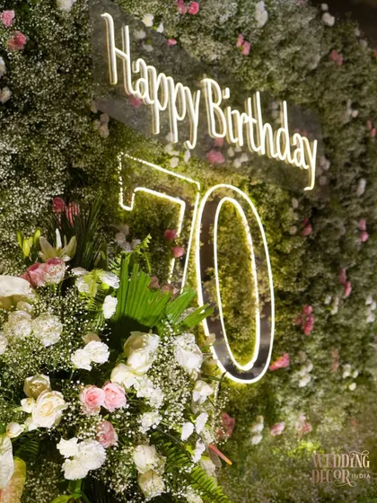 The custom "Happy Birthday 70" neon sign embedded within a wall of delicate baby's breath. This was a modern and beautiful way to highlight the milestone.