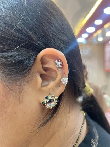 A sweet and sparkling ear combination with a floral helix stud and a heart-shaped hanging, perfect for a romantic look.