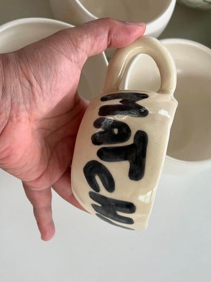 A fun, hand-painted "Matcha" mug that was part of the custom cafe order. The bold, simple lettering has a playful feel.