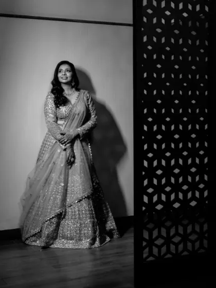 A classic, full-length bridal portrait in black and white, using shadows and light to create a dramatic and elegant image.
