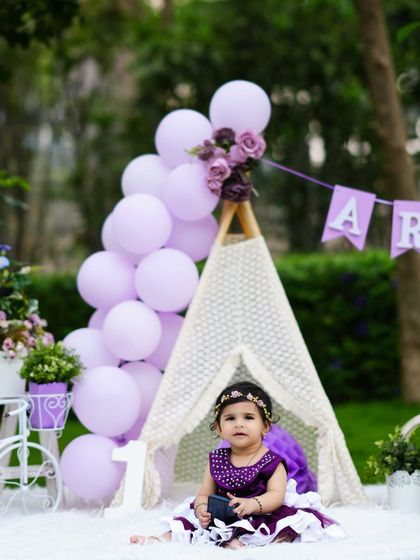 Another angle of Arohi's lovely first birthday shoot, showing the full outdoor setup with her sitting inside the teepee.