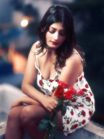 A pensive and beautiful portrait with a soft, painterly quality. The blurred city lights in the background add to the romantic, twilight mood.