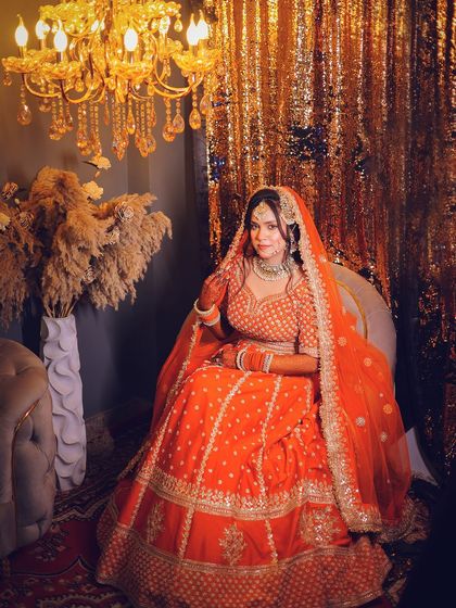 A full-length portrait showing the bride seated, with the grand decor providing a luxurious backdrop.