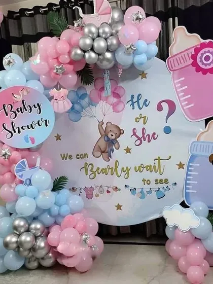 A detailed look at the "Bearly Wait" baby shower theme, perfect for a home setting. The round backdrop is surrounded by pink, blue, and silver balloons, with cute baby-themed cutouts.
