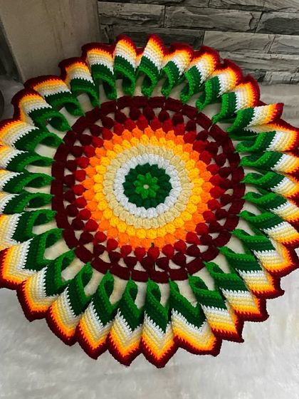 This is a traditional 'Tatavarcha Rumal', a decorative cover for a food plate, which I've handmade with crochet. The vibrant, multi-colored design with 3D petals makes it a beautiful centerpiece for any pooja or meal.