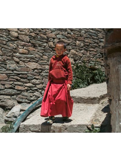 A young monk stands on a stone staircase, offering a curious look. These are the moments I seek, natural and unstaged.