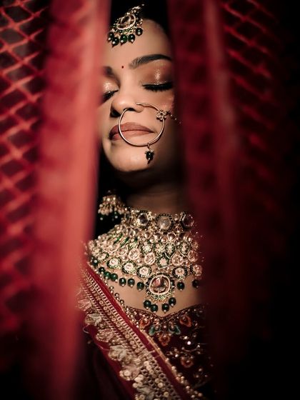 A close-up of a bride looking through her red veil, a classic shot that is both intimate and traditional.