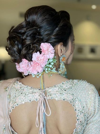 For this bride, I created a textured updo and decorated it with soft pink carnations and baby's breath, a delicate and feminine combination.