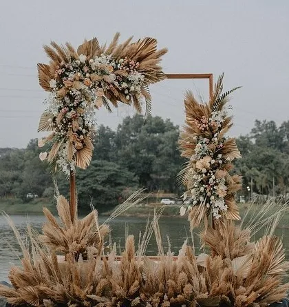 A modern, geometric arch decorated with pampas grass and white florals, creating a chic photo point for the anniversary celebration.