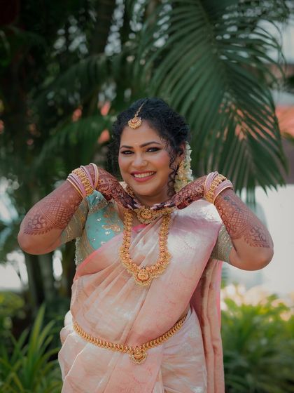 A cheerful portrait of the bride, her hands playfully framing her chin. Her bright smile and traditional attire capture the celebratory mood of her engagement day.