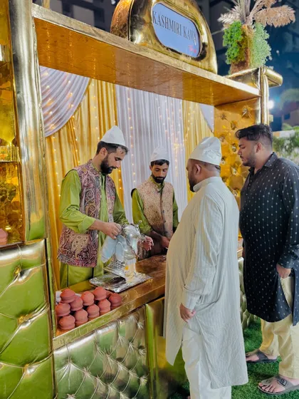 A guest is served a cup of hot Kashmiri Kahwa from a traditional samovar.