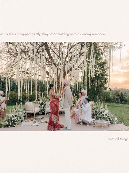 As the sun sets, the couple exchanges garlands under a beautifully decorated tree. This photo captures the dreamy, romantic atmosphere of a golden hour ceremony.