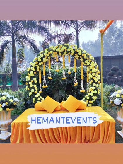 A bright and sunny Haldi seating area. The yellow velvet sofa is complemented by a circular arch of yellow flowers and matching cushions.