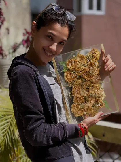 Here I am, holding a finished rectangular frame filled with beautifully arranged yellow roses. It makes me so happy to see a client's memories preserved forever.