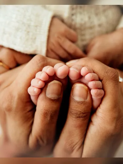Another beautiful angle of parents' hands holding their baby's feet, showing the texture and wrinkles that are so unique to newborns.