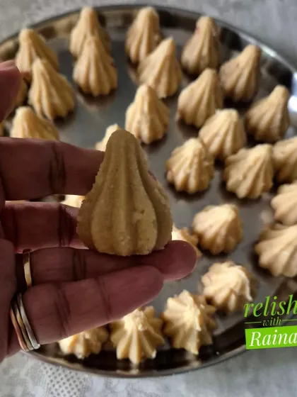 A perfectly shaped Rava Modak, made especially for the Ganpati festival. These are crafted from fine semolina, ghee, and jaggery, and flavored with cardamom and nuts, offering a soft texture that just melts in your mouth.