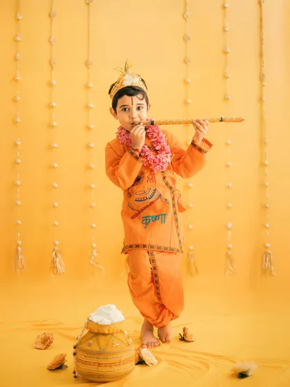 Celebrating traditions is close to our heart. This little one is dressed as Krishna for a Janmashtami themed photoshoot, complete with a flute and a pot of butter against a vibrant yellow backdrop.