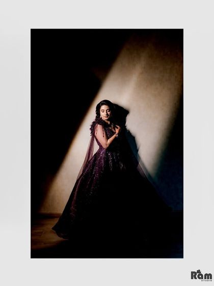 A stunning, low-light portrait of the bride in her dark gown. The single light source creates a dramatic, spotlight effect that is both artistic and beautiful.