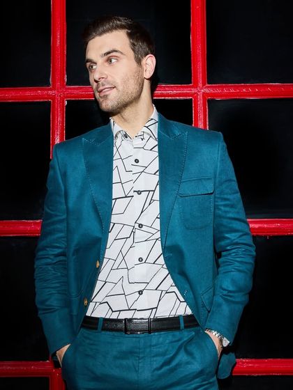 The teal green linen suit against a contrasting red background. The modern geometric print shirt adds another layer of style, showing how to pair bold pieces with confidence.