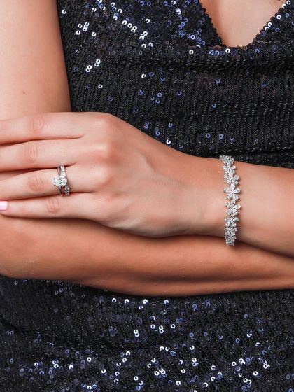 A lifestyle shot of a model wearing a sparkling diamond ring and bracelet set against a sequined dress. This image perfectly captures the glamour and elegance of the jewelry for an evening look.