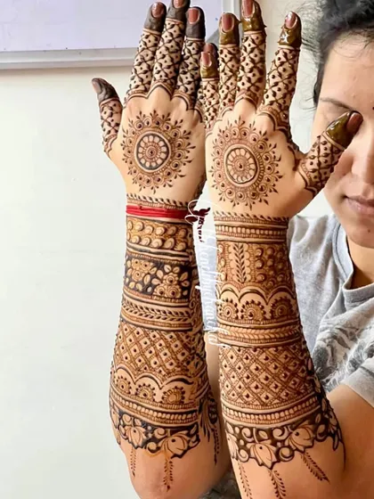 Full coverage mehendi for a baby shower, with traditional mandala designs on the palms and intricate patterns covering the arms.