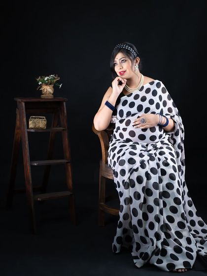 A retro-inspired maternity shoot. This mom-to-be looks chic and stylish in a black and white polka dot saree, proving that traditional wear can also be playful and modern.