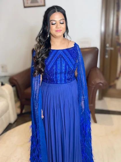 A beauty in blue. This client is ready for a party with soft, shimmery eyes, a pop of pink on the lips, and gentle curls.