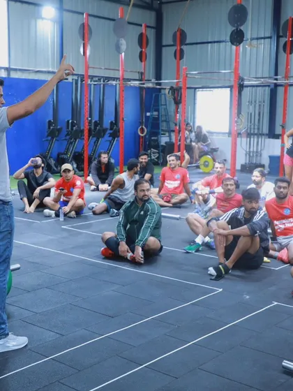 A coach briefs the athletes before a workout, explaining the movement standards and strategy. Clear communication is key to a successful event.