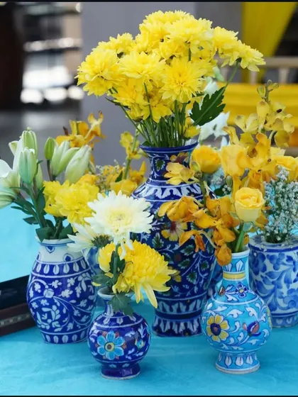 A collection of blue pottery vases with bright yellow flowers. This is a great way to incorporate traditional crafts into your event decor.