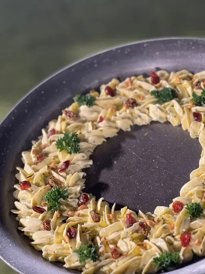 A festive butter board wreath, beautifully piped and garnished with parsley and cranberries, perfect for a holiday celebration.