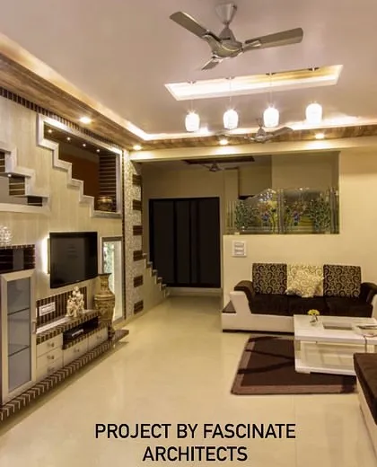 This large living room in Kharghar features an elaborate TV unit integrated with a staircase design. The use of mosaic tiles and multiple ceiling levels adds texture and dimension to the space.