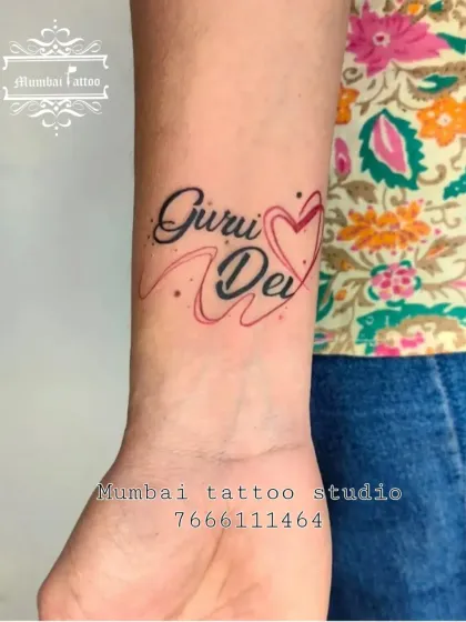 The name "Guru Dev" integrated with a heart, using both black and red ink to make the design pop. We love adding creative touches to make your name tattoos unique.