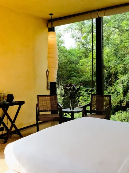 The full view of a suite, showing the spacious layout, minimalist furniture, and the all-encompassing view of the Asola Biosphere.