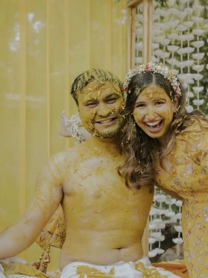 A candid moment of pure happiness. After being covered in turmeric paste, the couple shares a joyful, messy hug, showcasing the fun and intimacy of the Haldi ceremony.