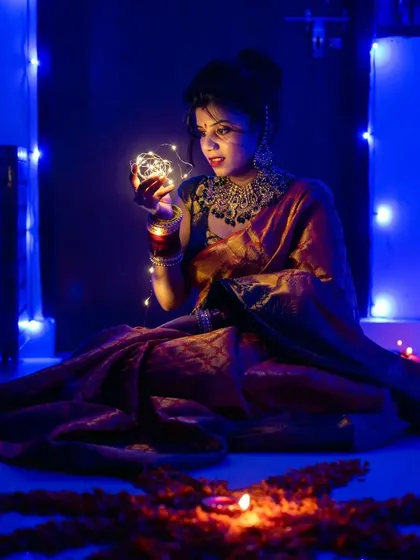 A beautiful Diwali portrait, with the woman holding fairy lights and a diya illuminating the scene.