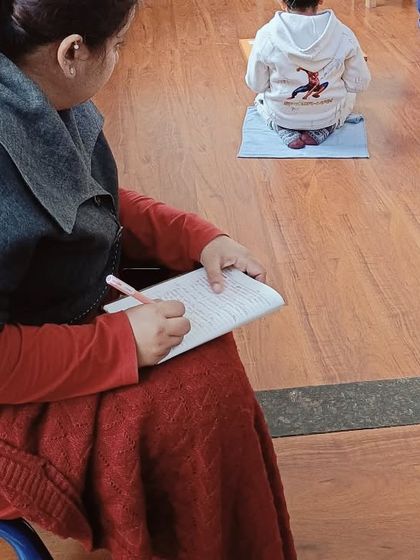 A trainee takes detailed notes while observing the classroom. These observations are not casual glances; they are scientific records of a child's development, concentration, and interaction with the materials, forming the basis for future lessons.