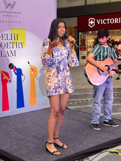 A young poet performing with a guitarist, showcasing the blend of simple, profound poetry and music that our audiences love.