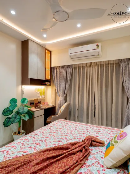 A bedroom designed with a compact study table and overhead storage, perfect for a student or professional.