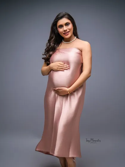 A confident and radiant portrait. The simple elegance of the pink satin gown allows the mother's joyful expression to shine.