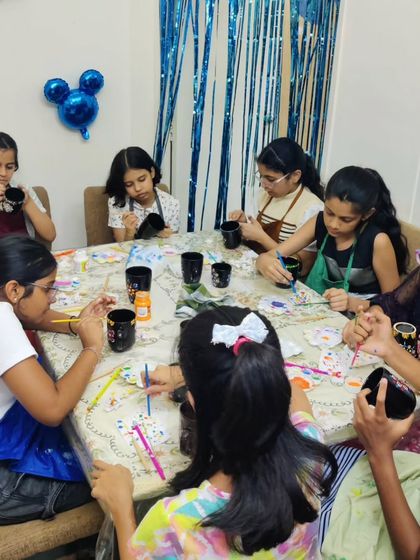 A candid shot of the kids deeply focused on their dot mandala mug painting during Amaira's birthday celebration.