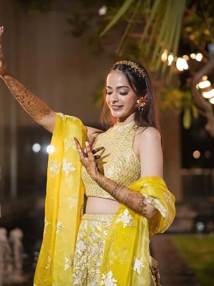 A happy, dancing bride at her mehendi ceremony, her henna-covered hands adding to the beauty of her movements.