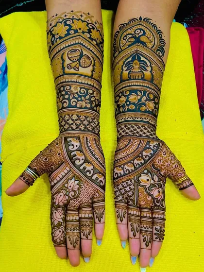 This design features a beautiful mix of peacocks, elephants, and kalash motifs. The use of color in the henna adds a unique and modern touch.