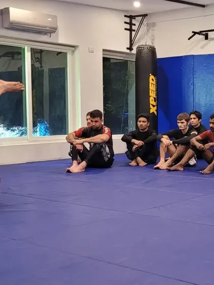 A student works on passing the guard while the coach observes. This is a fundamental part of Jiu-Jitsu, learning how to navigate through an opponent's legs to achieve a more dominant position.