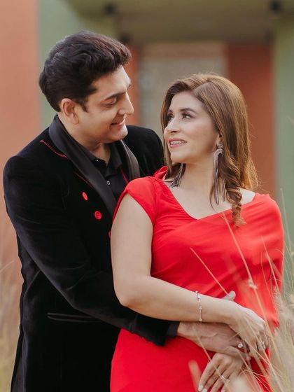 A romantic post-wedding anniversary shoot. The makeup is subtle and elegant, with a touch of Bollywood flair to match her red saree.