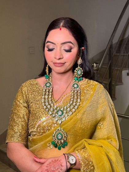 A soft, elegant look for this wedding guest. The makeup features a subtle smokey eye and a nude lip, allowing her stunning polki jewelry to take center stage.