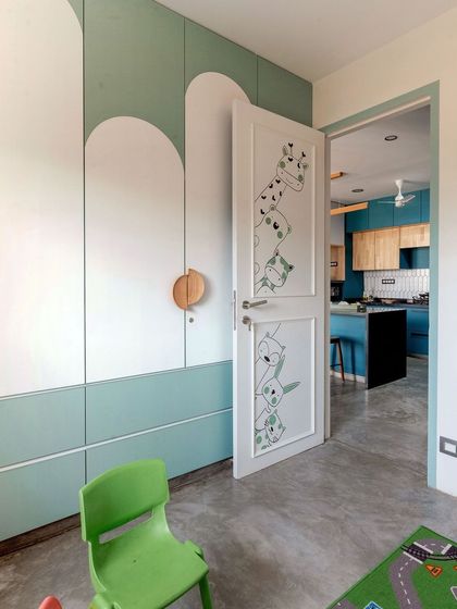 The custom wardrobe in the kids' room, with playful peek-a-boo animal illustrations on the door, connecting it to the kitchen view beyond.